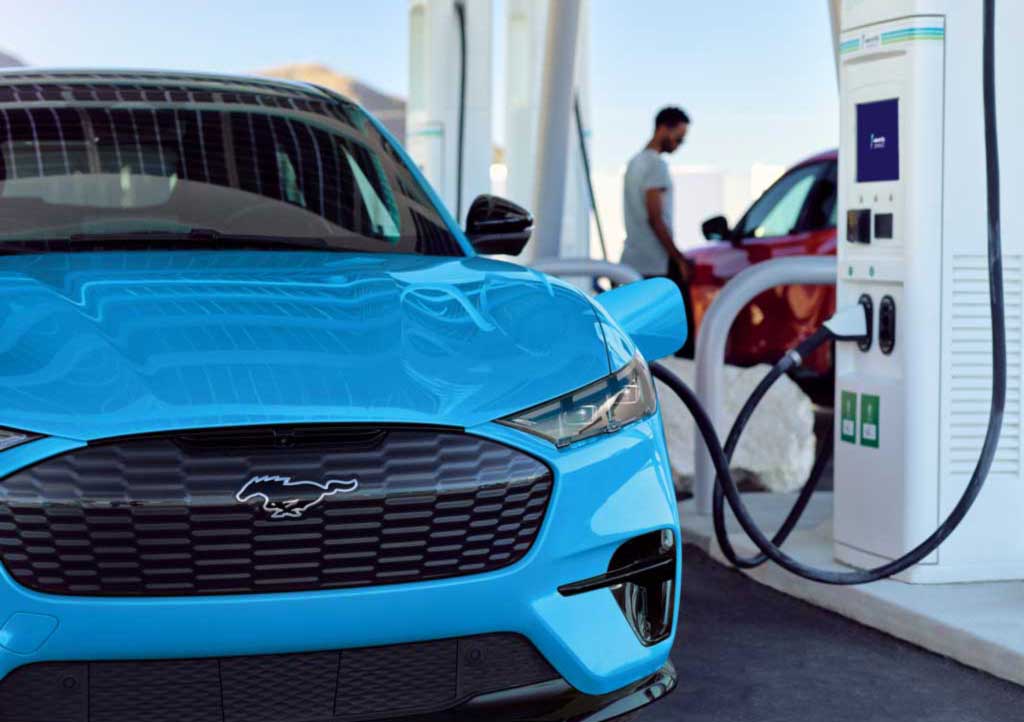 A Ford Mustang Mach-E in grabber blue at a public charge station getting charged