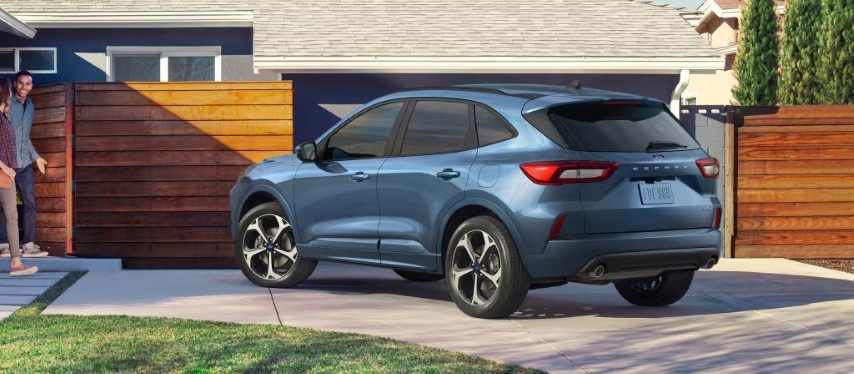 2025 Ford Escape parked in a residential driveway with a couple opening a wooden gate.