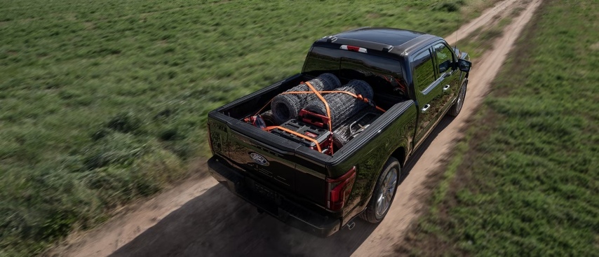 Ford Super Duty truck hauling fencing supplies and gear down a dirt road, supporting farm and 4H work in Southern Oregon.