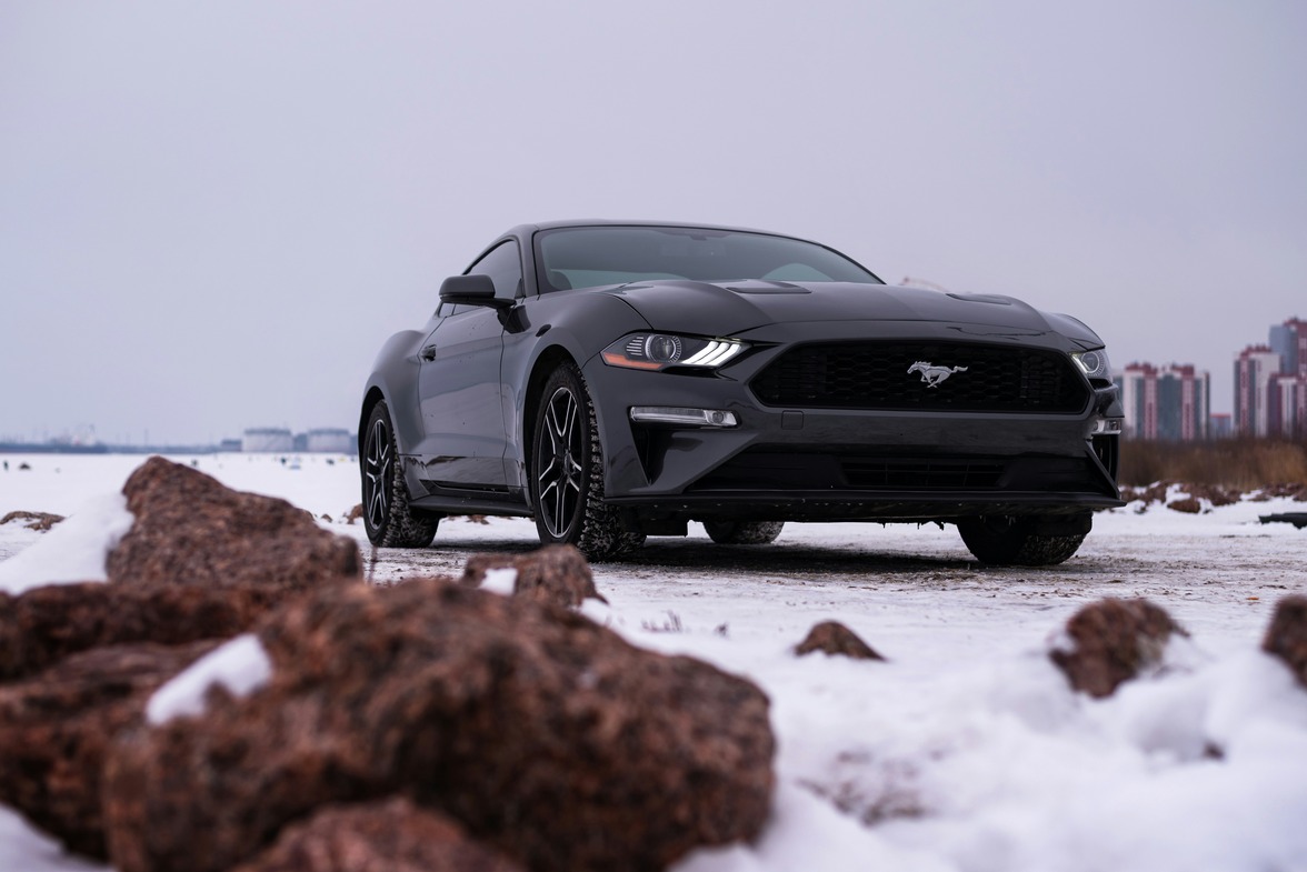 black mustang parked on a snowy road